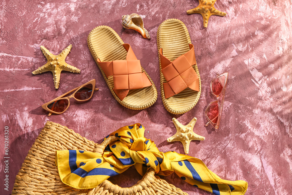 Female stylish flip flops with beach accessories on grunge pink background