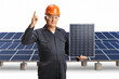 © Ljupco Smokovski - Technician in a uniform holding a photovoltaic panel and pointing up
