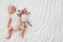 Little Cute Baby With Toy Sleeping On Bed At Home