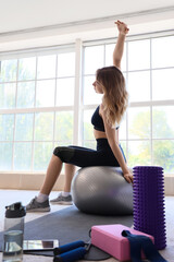 Sticker - Young sporty woman stretching with fitness ball during training at home