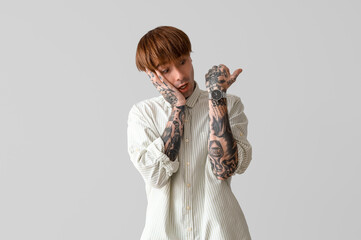 Wall Mural - Afraid young tattooed man on grey background