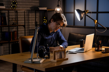 Poster - Young businessman writing in notebook at office