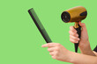 © Pixel-Shot - Female hands with hair dryer and comb on green background