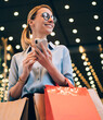 Positive female customer in eyeglasses enjoying good mood after spending day for shopping 