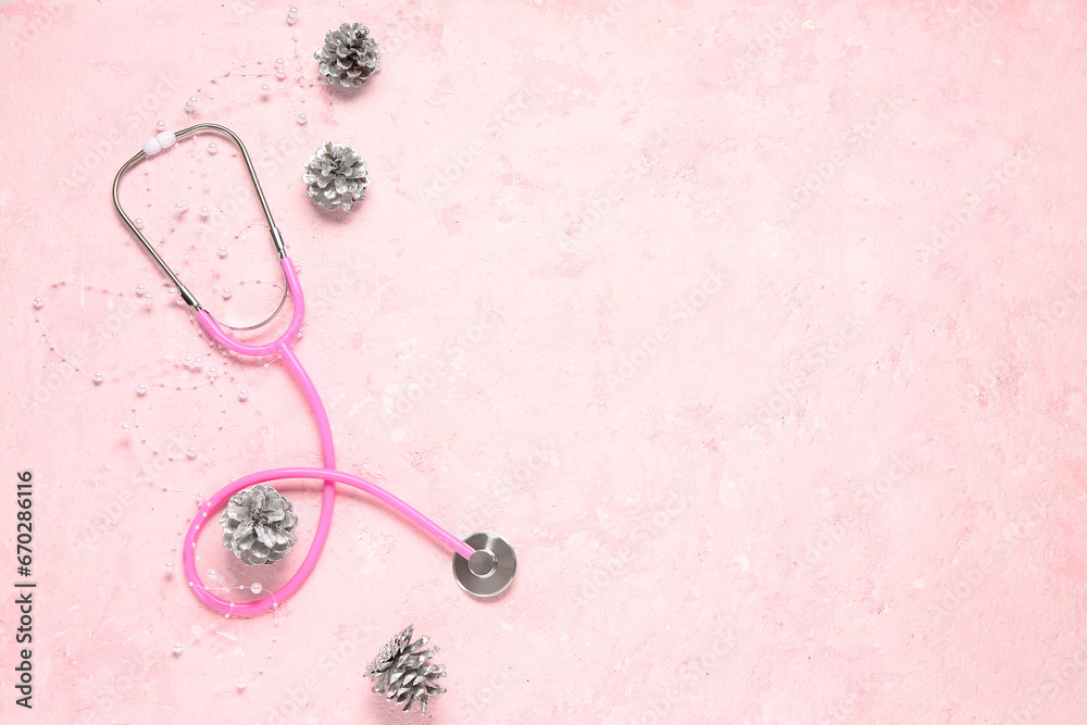 Christmas composition with stethoscope and pine cones on pink grunge background