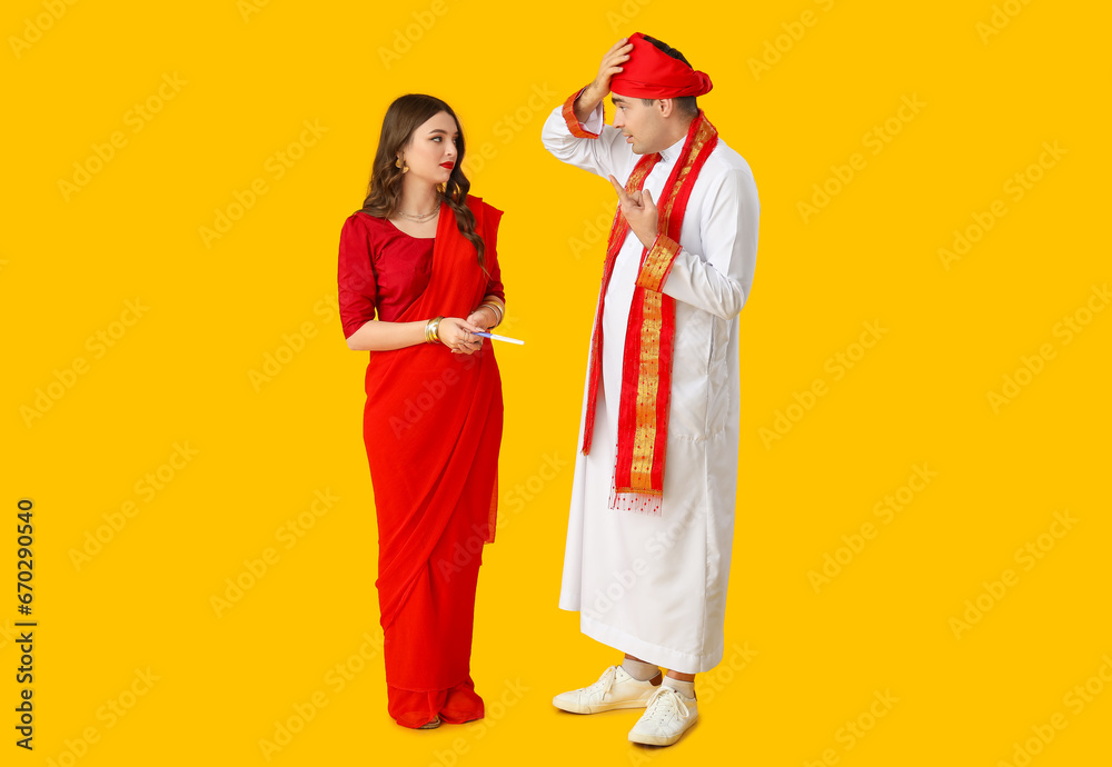 Terrified Indian couple with pregnancy test on yellow background