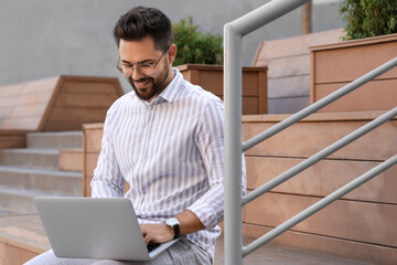 Sticker - Handsome young man using laptop on bench outdoors