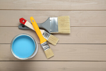 Wall Mural - Can of light blue paint and brushes on wooden table, flat lay. Space for text