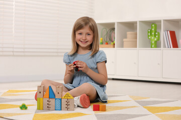 Poster - Cute little girl playing with wooden toys indoors, space for text