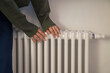© DimaBerlin - Woman warming hands near radiator at home after walking in cold winter weather, female touching barely warm battery during heating season, person near window checking heating system