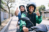 Fototapeta  - Young Asian commercial online taxi driver and female passenger showing thumbs up to camera