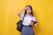 Asian female student in school uniform holding books and touching head forget about something