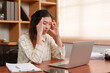 © Ekkasit A Siam - asian woman An office worker is using both hands to gently massage the forehead. After concentrating on working with a laptop computer With the boredom of routine work Have headache because of stress