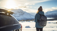 Portrait of happy traveling young woman standing near the car enjoying the view of snow mountain landscape, winter vacation outdoors
