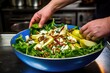 chefs hand tossing pear and blue cheese salad in a large salad bowl