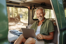 Happy Older Man Sitting In Rv Camper Van Using Laptop. Smiling Mature Active Traveller Holding Computer On Lap Remote Working Online And Enjoying Freedom, Resting In Outdoor Camping