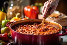 Hand Stirring A Pot Of Mexican Chili