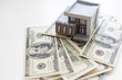 paper house model on background of US dollars banknotes. Housing market, purchase or rental of real estate