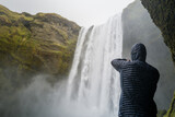 Man taking photos while visiting Skogafoss waterfall in Iceland