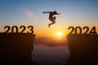 Happy new year 2024 concept. Silhouette of man jump on the cliff between 2023 to 2024 years over sunset or sunrise background.