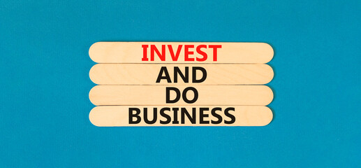 Invest and do business symbol. Concept word Invest and do business on beautiful wooden stick. Beautiful blue table blue background. Invest and do business concept. Copy space.