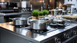Empty restaurant kitchen with large gas stove and numerous stainless steel pots