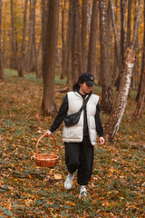 Sticker - woman with basket looking for mushrooms in autumn forest