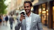 © visoot - Smiling businessman using smartphone on city street.