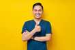 © Bangun Stock Photo - Professional young Asian male doctor or nurse wearing a blue uniform showing thumb up or like, looking at camera with smile isolated on yellow background. Healthcare medicine concept