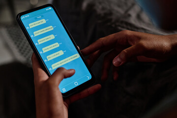 Screen of smartphone held by depressed African American teenage girl with anonymous messages containing cyberbullying stuff