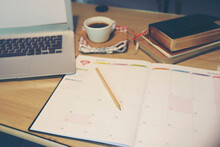 Agenda, planner book, laptop, 2024 calendar, pencil, and cup of coffee place on business office desk. Diary for organizer to plan timetable, daily appointment, and management job at room.