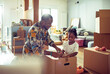 © Marko Geber - Father and daughter sealing a cardboard box together in the living room