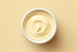 Ceramic dipping cup of cheese sauce, top view. Light yellow background. Minimalism.