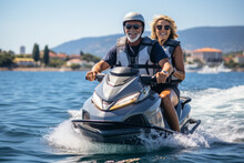 Happy Senior Caucasian Couple In Safety Helmets And Vests Riding Jet Ski On A Lake Or Along Sea Coast. Active Elderly People Having Fun On Water Scooter. Healthy Lifestyle For Retired Persons.