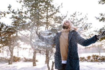 Wall Mural - Young stylish man in a snowy forest. Handsome man enjoying sunny winter weather. Concept of people, vacation.