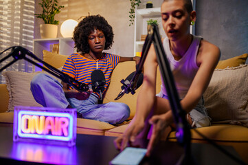 Wall Mural - Two multiracial women recording episode of internet podcast in a modern studio