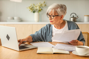 Middle aged senior woman sit with laptop and paper document, Pensive older mature lady reading paper bill pay online at home managing bank finances calculating taxes planning loan debt pension payment