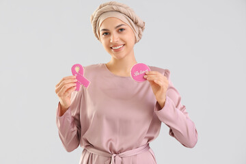 Canvas Print - Young woman after chemotherapy with cookies on light background. Breast cancer awareness concept