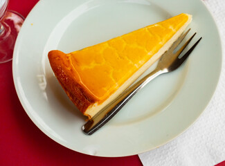 Poster - Triangle piece of cheesecake with yellow gelatin glaze dished up in white service plate