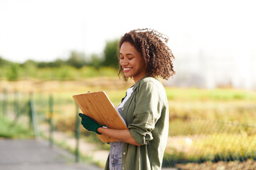 Wall Mural - Female farmer making notes in clipboard on field during harvesting. Agricultural concept