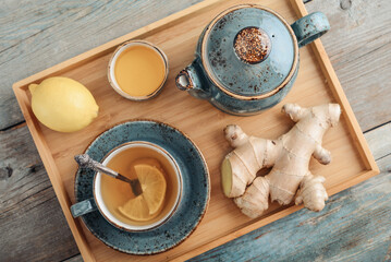 Wall Mural - Ginger tea with lemon and honey in a blue cup on a bamboo tray