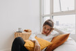 © Sevendeman - Happy asian woman sit and relax on bean bag in living room by the windows.