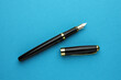 Stylish fountain pen with cap on light blue background, flat lay