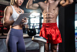 Fototapeta  - Asian young fitness trainer support sportsman doing boxing in gym club.  