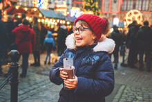 Little Cute Preschool Girl Drinking Hot Children Punch Or Chocolate On German Christmas Market. Happy Child On Traditional Family Market In Germany, Laughing Kid In Colorful Winter Clothes
