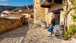 Tourist woman resting and sunbathing next to an old house in the village of Frias, Spain.