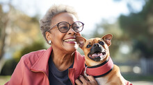 A Senior African American Woman Playfully Holding Her Dog In Park. Love For Animals Concept.
