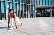Fitness woman in sports clothing. Sexy young beautiful model athlete doing fitness workout. Female making exercises in the street at sunny day. Stretching out before training. Makes lunges