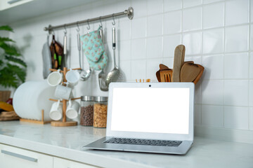 Wall Mural - Mockup of laptop computer with empty screen sugar, spices in glass jars eggs, vegetable,tomato and a whisk on the kitchen on white table. Flat lay. Concept of food preparation, on background.