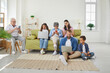 © Studio Romantic - Big family using different electronic devices while sitting on sofa at home. Grandparents, parents and children browsing internet, playing games or entertaining using mobile apps. Gadget addiction